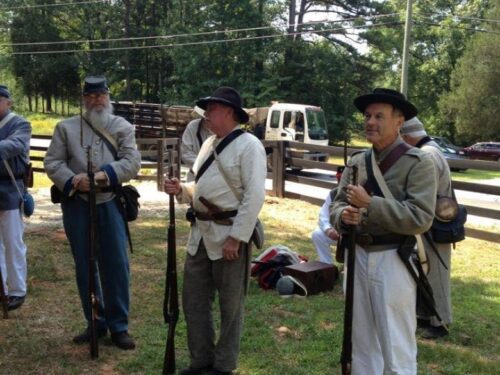 A group of men dressed in civil war attire, participating in a reenactment