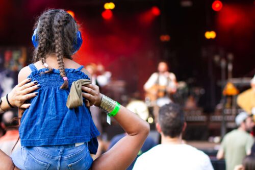 young girl enjoying a concert on her parent's shoulders