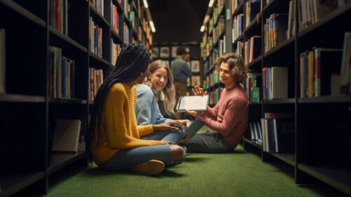 Diverse Group of teenagers, sitting on the floor of a library, hanging out