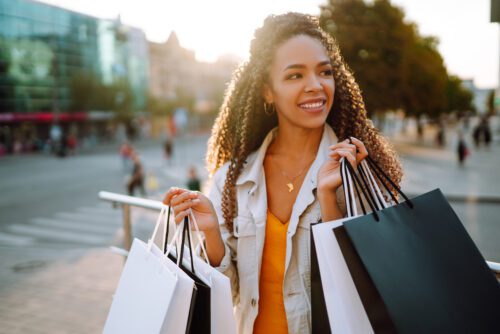 happy woman carrying shopping bags through a plaza