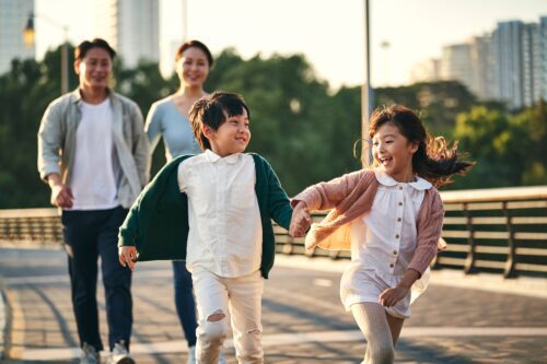 Happy Asian family taking a walk through the city on a pedestrian bridge in one of the best neighborhoods in atlanta for families