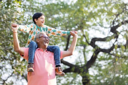 Grandfather carrying his grandson on his shoulders in the park