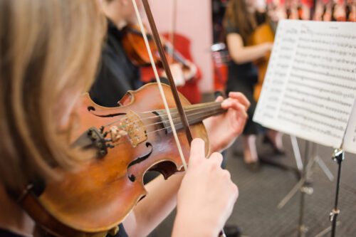 close up photo of a girl playing the violin in a school orchestra