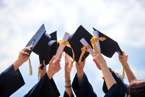 group of students holding their caps and diplomas after graduation from high schools in cherokee county