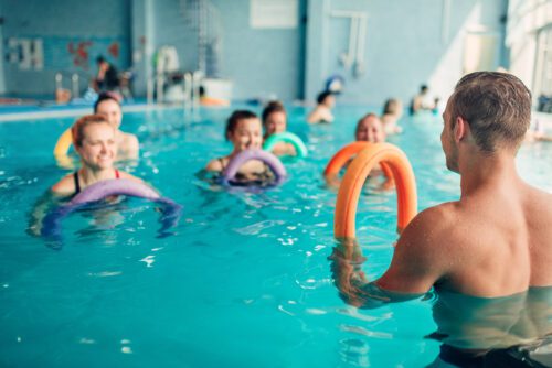 group of seniors in a pool being led by a fitness instructor in a water aerobics class