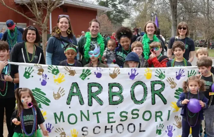students and teachers at Arbor Montessori School, holding up a parade banner and posing for a picture
